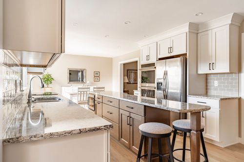 Kitchen with white cabinetry, wine cooler and wood-toned island opening to the dining room