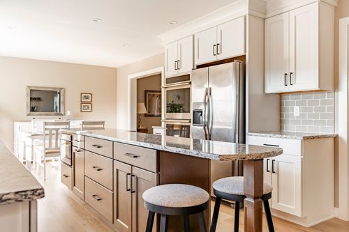 Kitchen with stainless double wall ovens, refrigerator and a wood-toned island