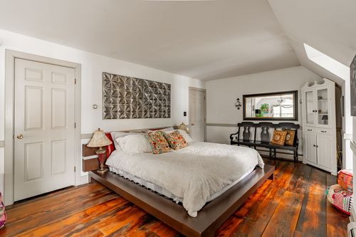 Bedroom with wood platform bed, tufted bench and antique mirror