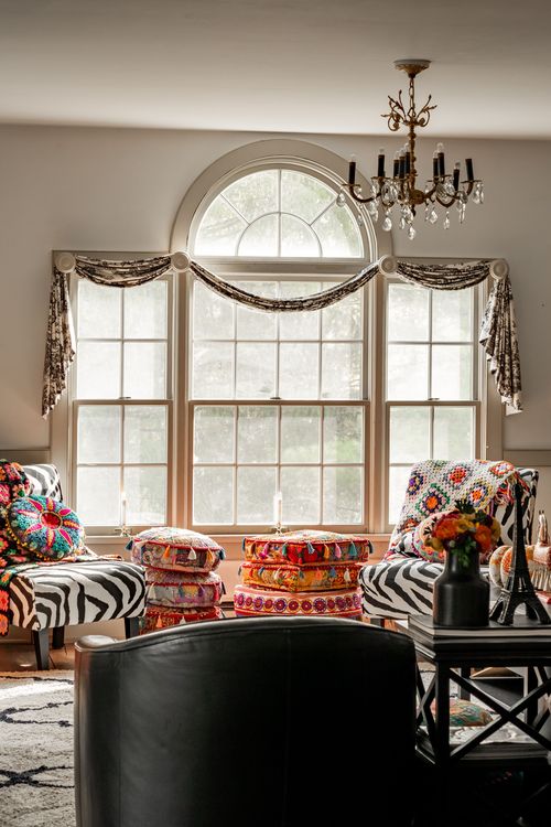 Living room with an arched window, zebra print chairs and crystal chandelier