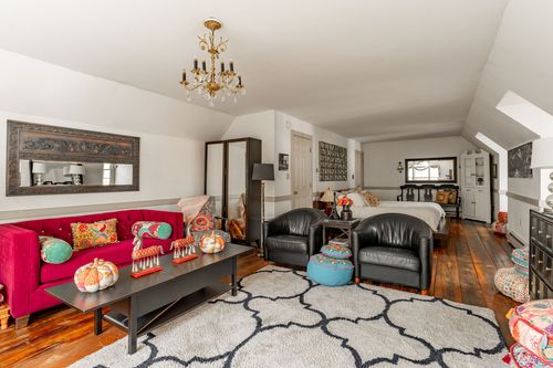 Vaulted living room with red sofa, black leather chairs and layered patterned rugs