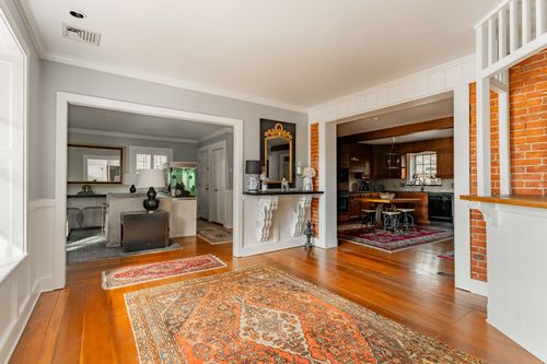 Entry hallway with wood paneling, brick accent wall and oriental rugs leading to the kitchen