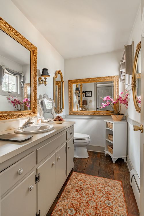 Bathroom with gold ornate mirrors, pink orchids and a patterned runner