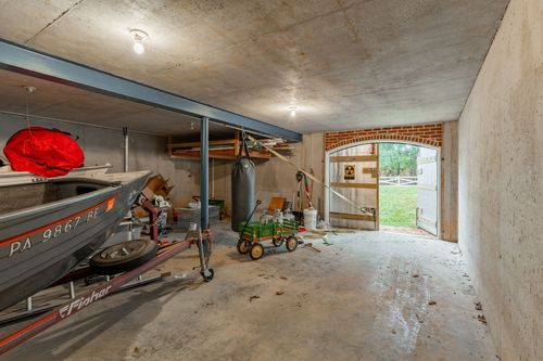 Garage interior with a boat on a trailer and an arched brick doorway to the yard