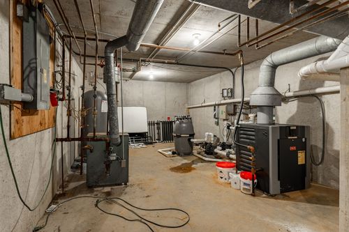 Basement mechanical room with furnace, water treatment tanks and exposed piping