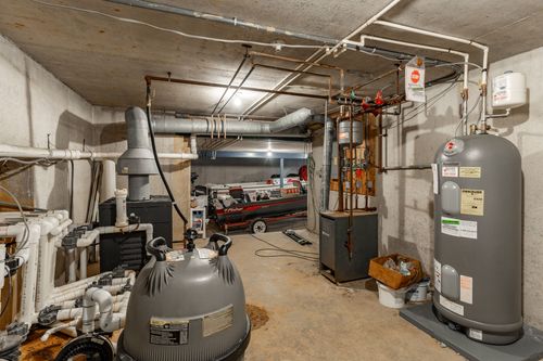 Basement utility room with water heaters, exposed pipes and a stored boat