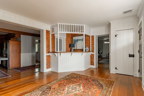 Foyer with white paneled walls, brick inset bar nook and a patterned area rug
