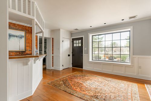 Front foyer with wainscoting, brick accents, a large window and oriental rug