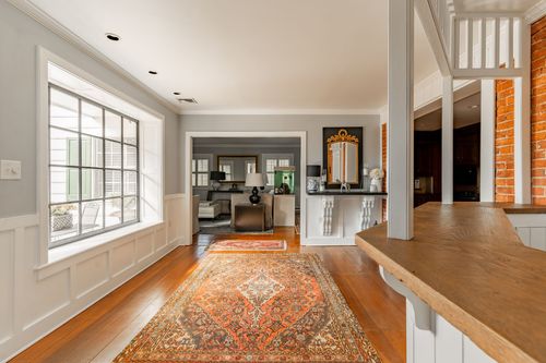 Hallway with staircase newel post, exposed brick wall and antique runner rug