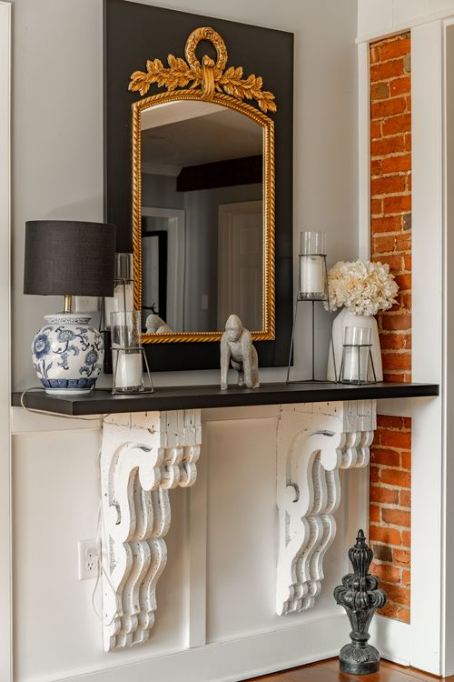 Console table vignette with gilt mirror, blue and white lamp and exposed brick wall