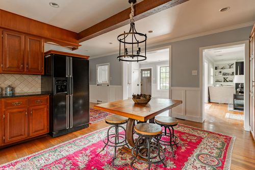 Kitchen and dining area with wood cabinetry, black refrigerator and a chandelier over the table