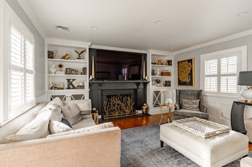 Living room with black fireplace mantel, mounted TV and built-in bookshelves
