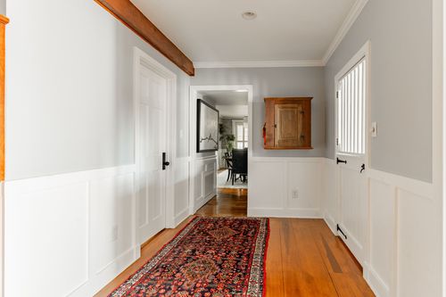 Hallway with wood beam ceiling accent, oriental runner rug and a built-in corner cabinet