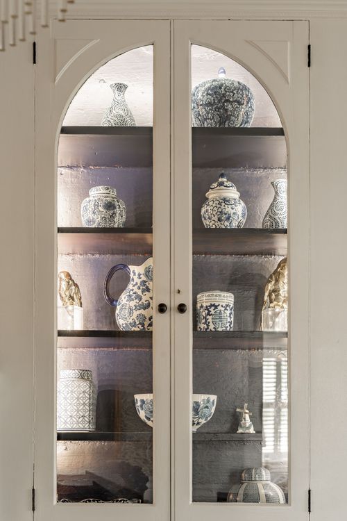 Built-in arched china cabinet displaying a blue and white porcelain collection