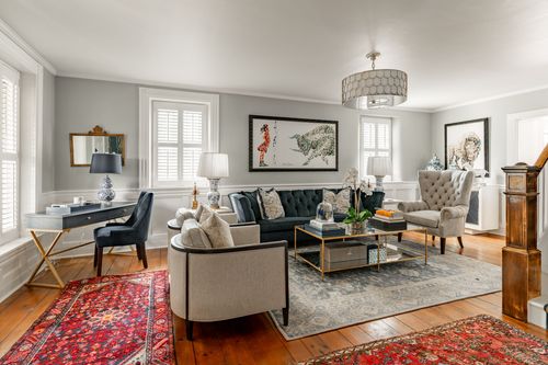 Living room with black tufted sofa, animal print artwork and a drum chandelier
