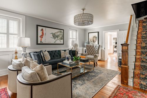 Living room with tufted sofa, framed artwork and view toward the staircase