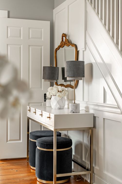 Entryway console table with gilt mirror, marble vase and velvet stools