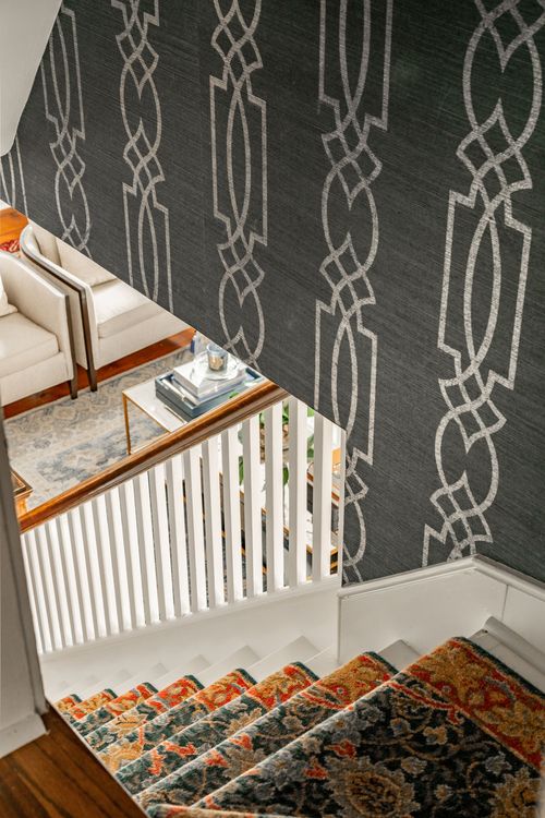 Staircase landing with geometric patterned wallpaper and an ornate runner rug