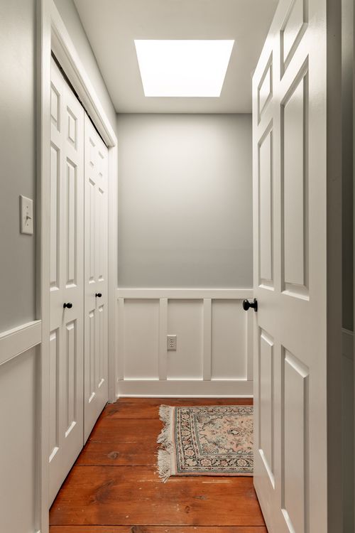 Hallway with skylight, white paneled closet doors and an oriental runner rug