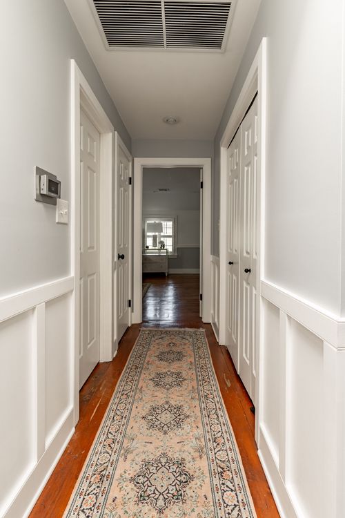 Hallway with white doors, closets and an antique runner rug on wood floors