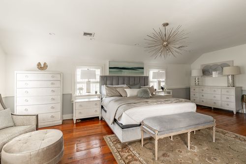 Bedroom with starburst chandelier, matching dressers and a tufted bench