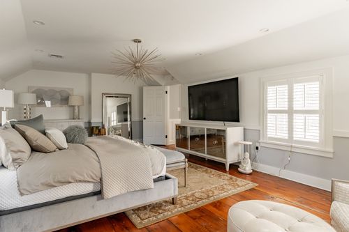 Bedroom with wall-mounted TV, mirrored dresser and starburst chandelier