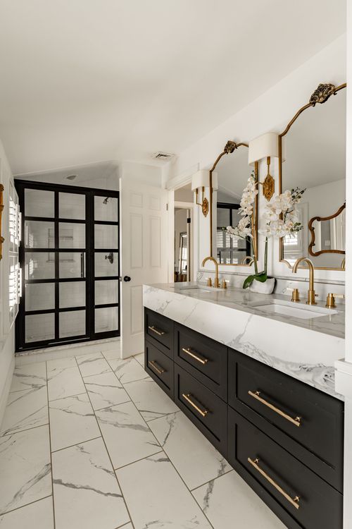 Bathroom with black glass shower door, marble tile floor and gold-accented black vanity