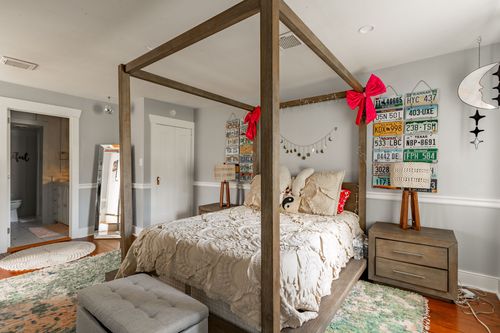 Bedroom with wood canopy bed, license plate collection and a crescent moon lamp