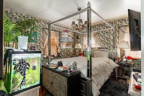Eclectic bedroom with mirrored canopy bed frame, floral wallpaper and a fish tank