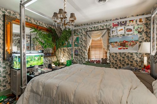 Eclectic bedroom with mirrored canopy bed, floral wallpaper and layered greenery