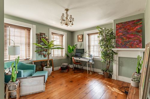 Home office with sage green walls, potted plants and a colorful abstract painting