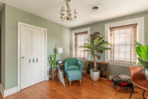 Sitting room with sage green walls, wingback chairs and tall potted plants