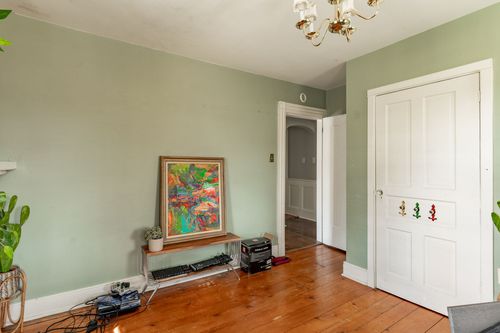 Sage green room with a vibrant painting, wood bench seat and chandelier