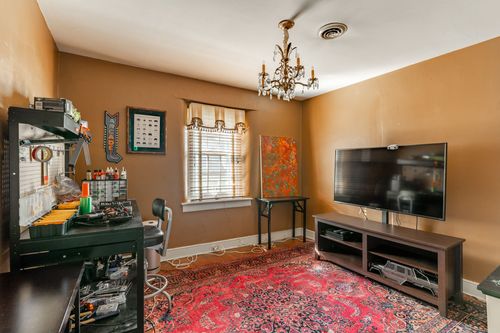 Hobby room with a workbench, framed artwork, wall-mounted TV and red oriental rug