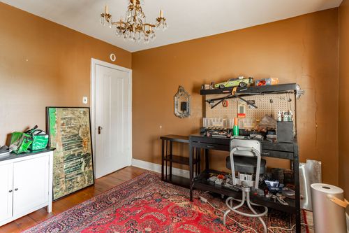 Craft room with a pegboard workbench, chandelier and layered red rug