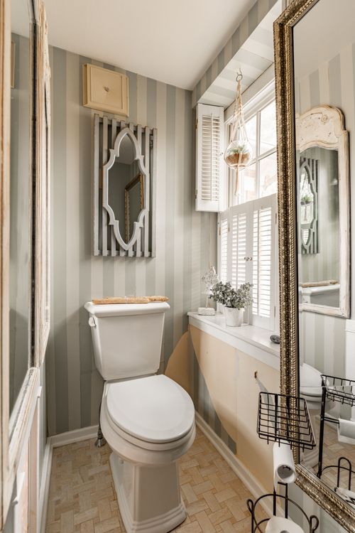 Powder room with striped wallpaper, ornate mirror and shuttered window