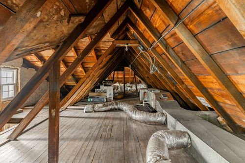 Attic space with exposed wood rafters and rough-cut plank flooring