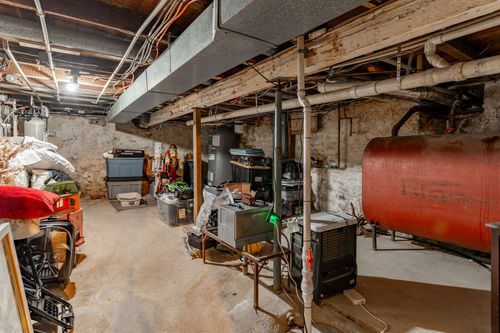 Basement with stone walls, ductwork and an old oil storage tank