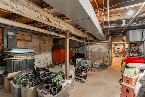 Basement storage area with wood beams, exposed pipework and oil tank