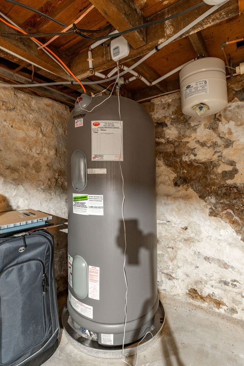 Basement with a large water heater tank set against exposed stone walls