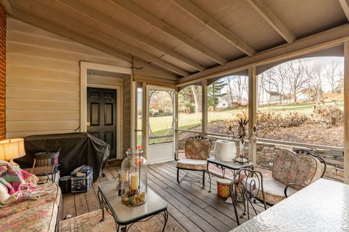 Screened porch with wood beam ceiling, wicker furniture and a lawn view
