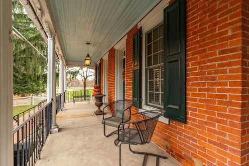 Covered brick farmhouse porch with wrought iron chairs and hanging lantern