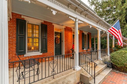 Brick porch entrance with black door, American flag and wrought iron railings