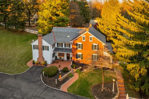 Aerial dusk view of a brick colonial home with white garage and curved brick walkway
