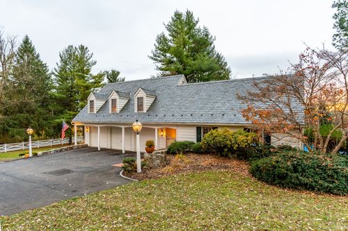 Aerial view of a shingled ranch house with dormer windows and attached three-car garage