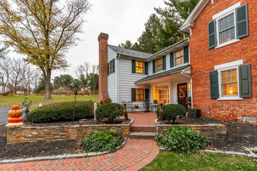 Farmhouse exterior with brick chimney, stone garden wall and brick front walkway
