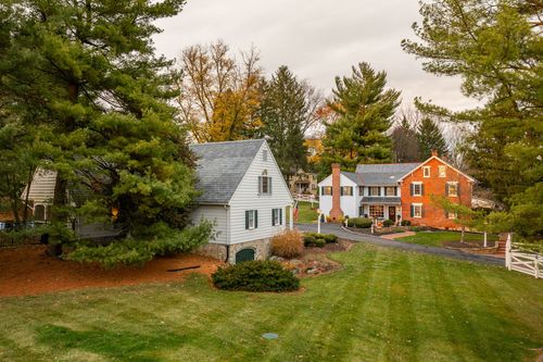 Aerial view of a stone outbuilding beside a white farmhouse and brick manor home