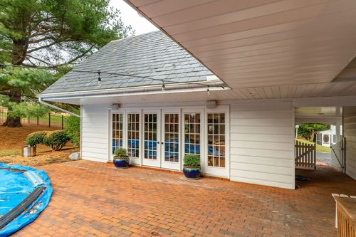 Brick patio with white French doors and potted topiaries under a covered roof