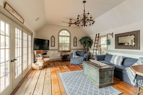 Vaulted living room with wood plank floors, blue sofa and wrought iron chandelier