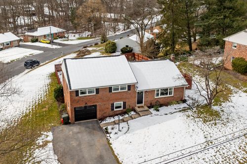 Aerial winter view of a brick split-level home with attached garage and snowy lawn